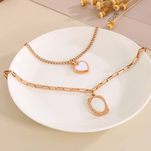 Detailed close-up of a double-layered rose gold necklace with white shell heart charms