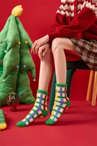 Close-up of thick coral fleece Christmas socks with festive plaid pattern on model