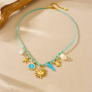 Flat lay of ocean-themed necklace with starfish, turtle and shell charms on beach sand