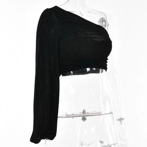 Détail du haut noir à une épaule et manches longues avec fronces sur le mannequin de couture