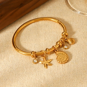 Detailed view of 18K gold plated stainless steel bangle with nautical charms and shells