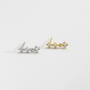Detail showing three linked clear cubic zirconia stones on gold and silver stud earrings