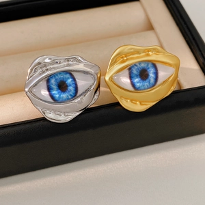 Macro detail of irregular gold and silver eye rings with realistic blue iris on velvet