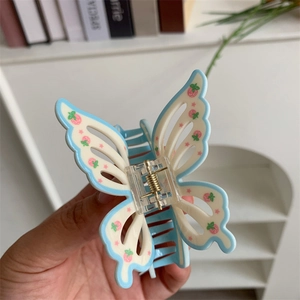 Detail showing blue and cream acrylic butterfly hair claw clip with pink strawberry pattern