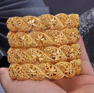 Detail of four gold hollow bracelets with intricate floral patterns and mesh texture