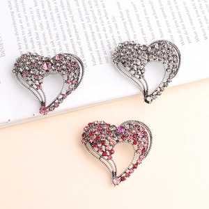 Detailed view of heart-shaped safety pin brooches with pink, red and grey rhinestones
