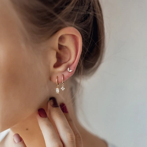 Close-up of three gold earrings with marquise leaves and sparkling cubic zirconia stones