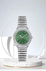 Detailed close-up of a silver rhinestone watch with a green dial on a stone display