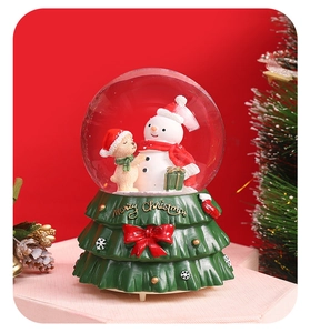 Detail view of snowman crystal ball with green Christmas tree base and red bow