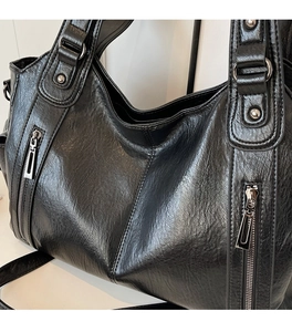 Detailed close-up of high-quality black faux leather texture and silver rivets on the bag