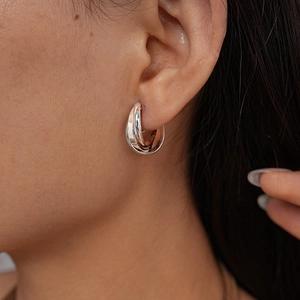 Detailed view of silver interwoven triple-ring clip earrings worn by a female model