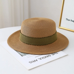 Chapeau de soleil en paille à bord large et ruban olive sur une table blanche