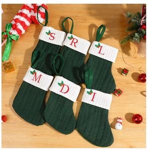 Macro detail of six green knitted Christmas stockings with red embroidered letters