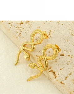 Detail of 18k gold plated snake earrings with scale texture on beige stone background