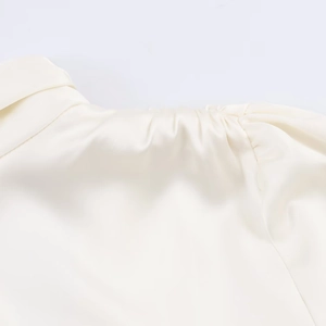 Dettaglio di elegante tessuto satinato avorio con pieghe delicate e trama di seta