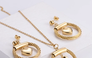 Detail of gold heart pendant and spiral ring jewelry set on white textured stone