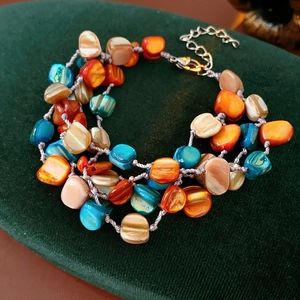 Macro detail of Bohemian multilayer shell bracelet with colorful beads and gold clasp
