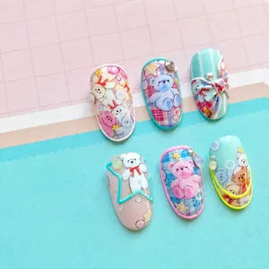 Macro shot of 5D embossed nail stickers featuring cute teddy bears and plaid patterns