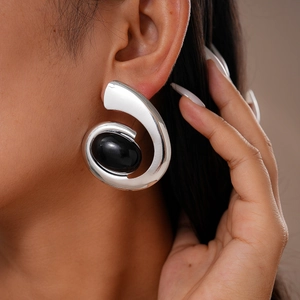 Close-up of silver irregular spiral earring featuring a bold black oval stone inlay