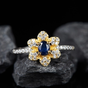 S925 sterling silver flower ring with blue gemstone and white zircon on stone background