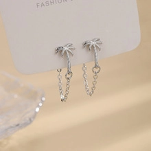 Dettaglio macro di orecchini a forma di palma in argento con lunghe nappe a catena