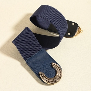 Macro detail of navy elastic waist belt with engraved gold metal buckle and leather trim