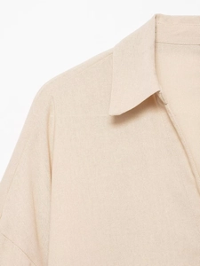 Gros plan de la chemise en lin beige avec col à revers et texture de tissu respirant