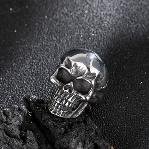 Detailed close-up of a realistic steel skull ring on a textured dark rock background