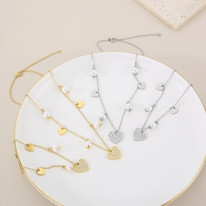 Detail view of gold and silver heart necklaces with pearls and crystals on a white plate
