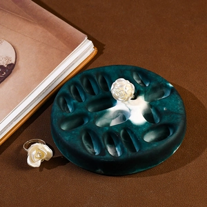 Detailed view of white rose flower rings displayed on a green marble vanity jewelry tray