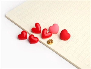 Detail of red and pink heart pins with golden butterfly clutch backings on a grid paper