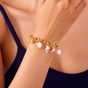 Close-up of a gold bracelet featuring starfish, seashell, conch, fishtail, and pearl charms