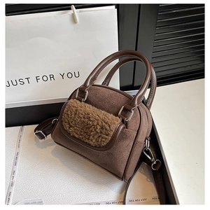 Close-up of dark brown suede handbag with plush shearling trim and silver hardware details