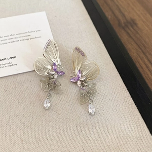 Detail view of silver butterfly earrings with purple crystals and sparkling tassels
