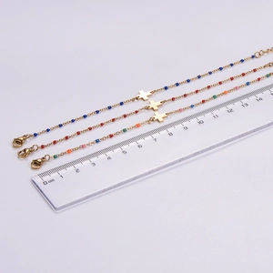 Dettaglio di bracciali con perline colorate e croce con righello per riferimento misura