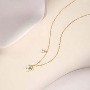 Close-up of gold necklace with star-shaped marquise stones and teardrop gemstone detail