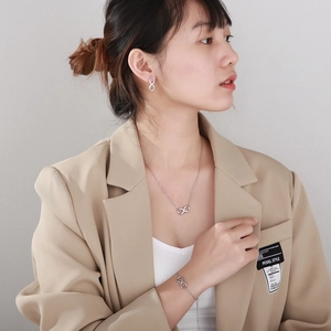 Model wearing silver infinity jewelry set including earrings, necklace and bracelet