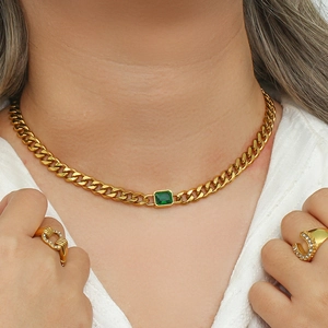 Detail showing gold Cuban chain necklace with green zircon pendant on model neck