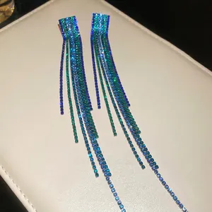 Elegant silver tassel earrings with gradient blue and green crystals on faux leather mat