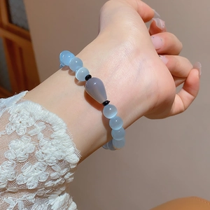 Close-up of cat eye stone bead bracelet worn with white lace sleeve details