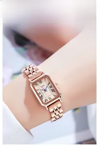 Close-up of elegant rose gold square watch with Roman numerals and blue hands on wrist