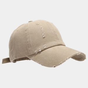 Detail of distressed khaki cotton baseball cap showing frayed holes and twill texture