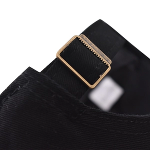 Detalle de la hebilla de bronce ajustable en una gorra clásica de algodón negro