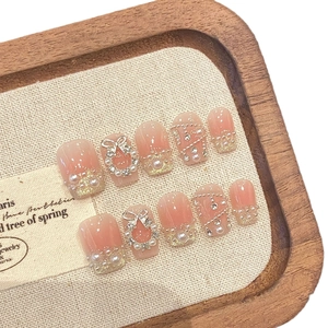 Pink blush press-on nails with 3D pearls, crystal bows, and gold glitter accents
