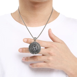 Close-up of vintage silver Viking wolf pendant featuring Norse runes on a man's neck