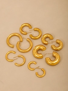 Vista macro de pendientes de aro en forma de C chapados en oro en varios tamaños claros