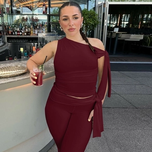Detail of burgundy off-shoulder tied top and matching slim trousers on model in bar