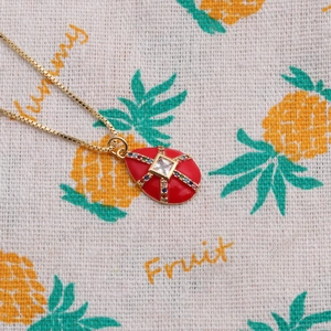 Detailed macro of gold plated necklace with a red enamel oval pendant and zircon cross inlay