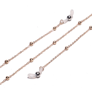 Close-up of golden metal eyeglass chain with small beads and clear silicone loops