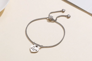 Close-up of adjustable stainless steel heart bracelet with Love engraving and bolo clasp